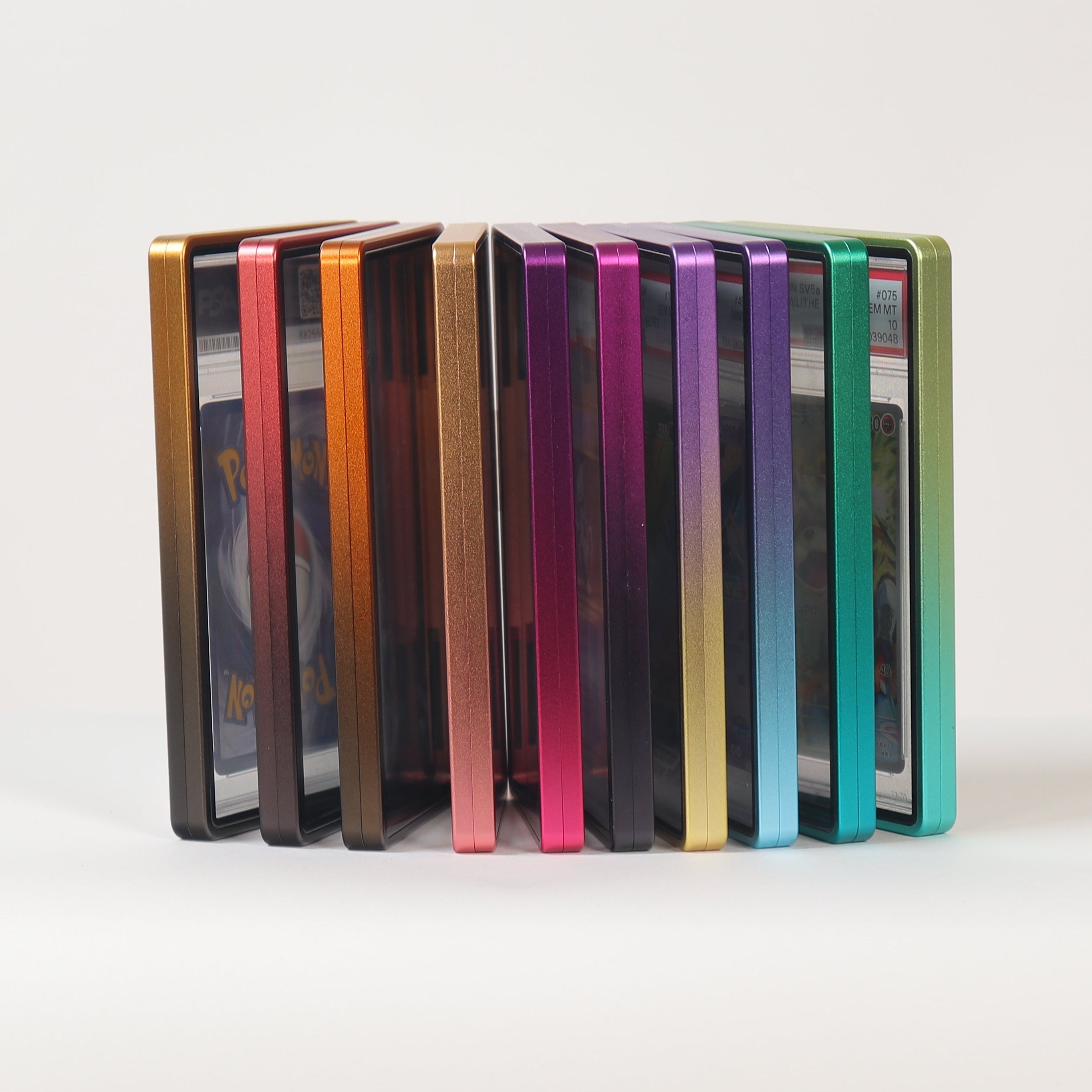 A set of slim rectangular cards or cases standing upright in a row on a white surface against a light gray background. The items display a spectrum of colors including gold, orange, pink, purple, blue, and green.