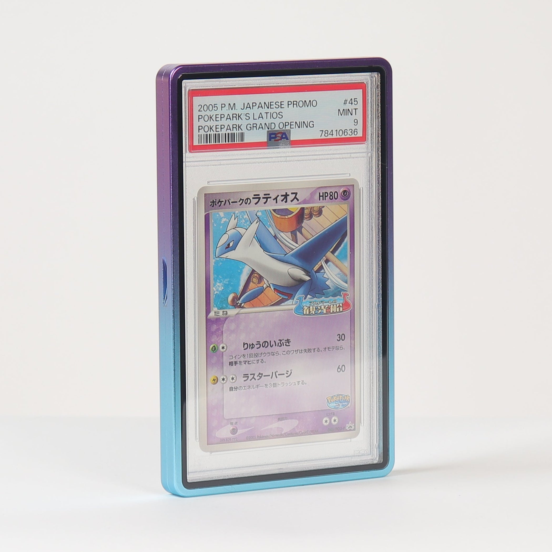 A graded Pokémon TCG card in a clear PSA-style plastic slab, standing upright on a white surface against a white background. The card features artwork of a blue bird-like creature and has a purple-toned border visible around the slab.