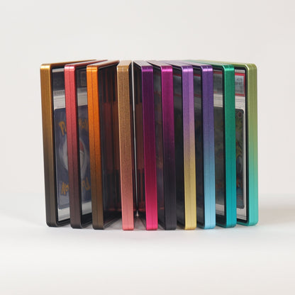 A set of slim rectangular cards or cases standing upright in a row on a white surface against a light gray background. The items display a spectrum of colors including gold, orange, pink, purple, blue, and green.