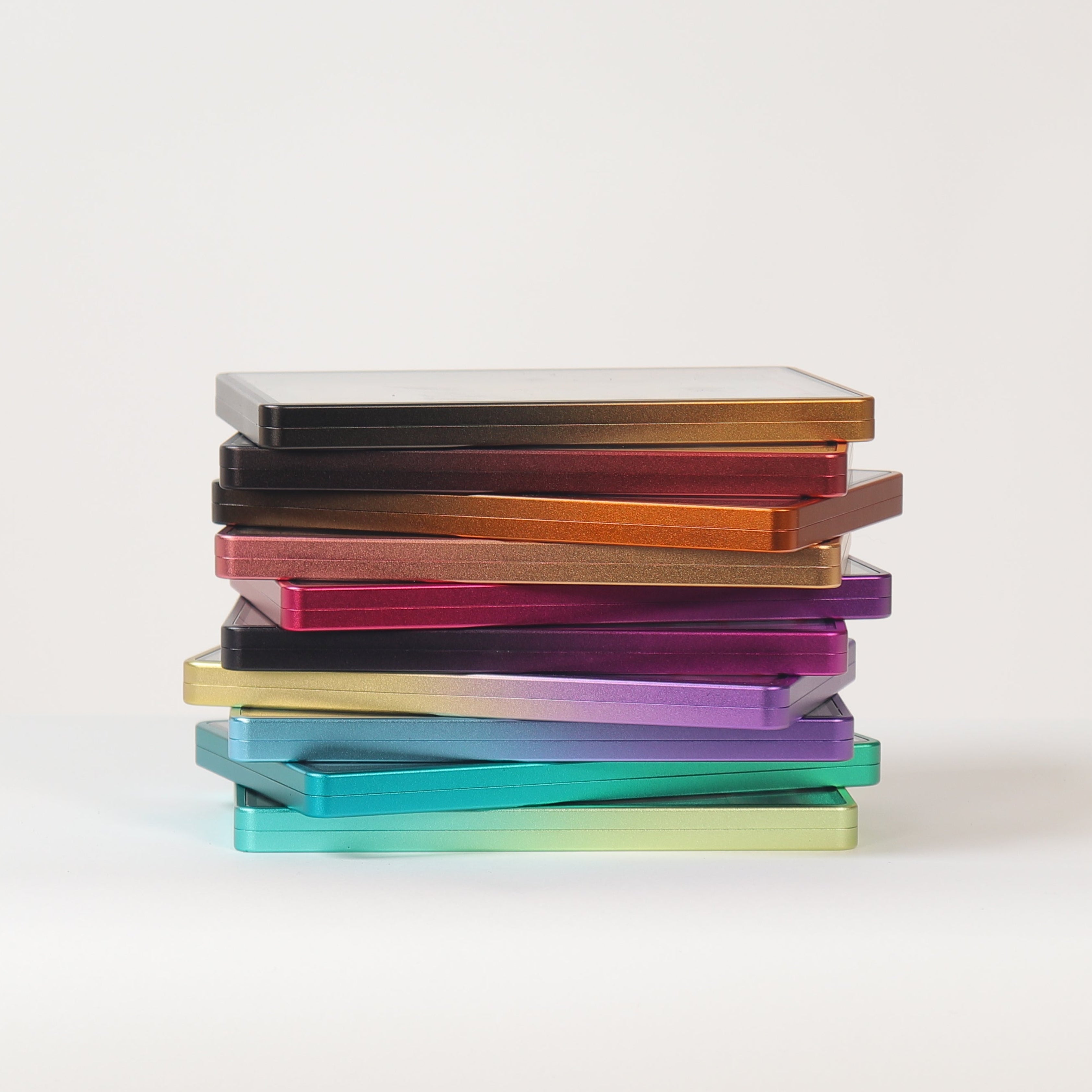 A stack of six slim rectangular cards or booklets in different colors, including black, orange, red, yellow, purple, and teal, arranged vertically on a white surface against a white background.